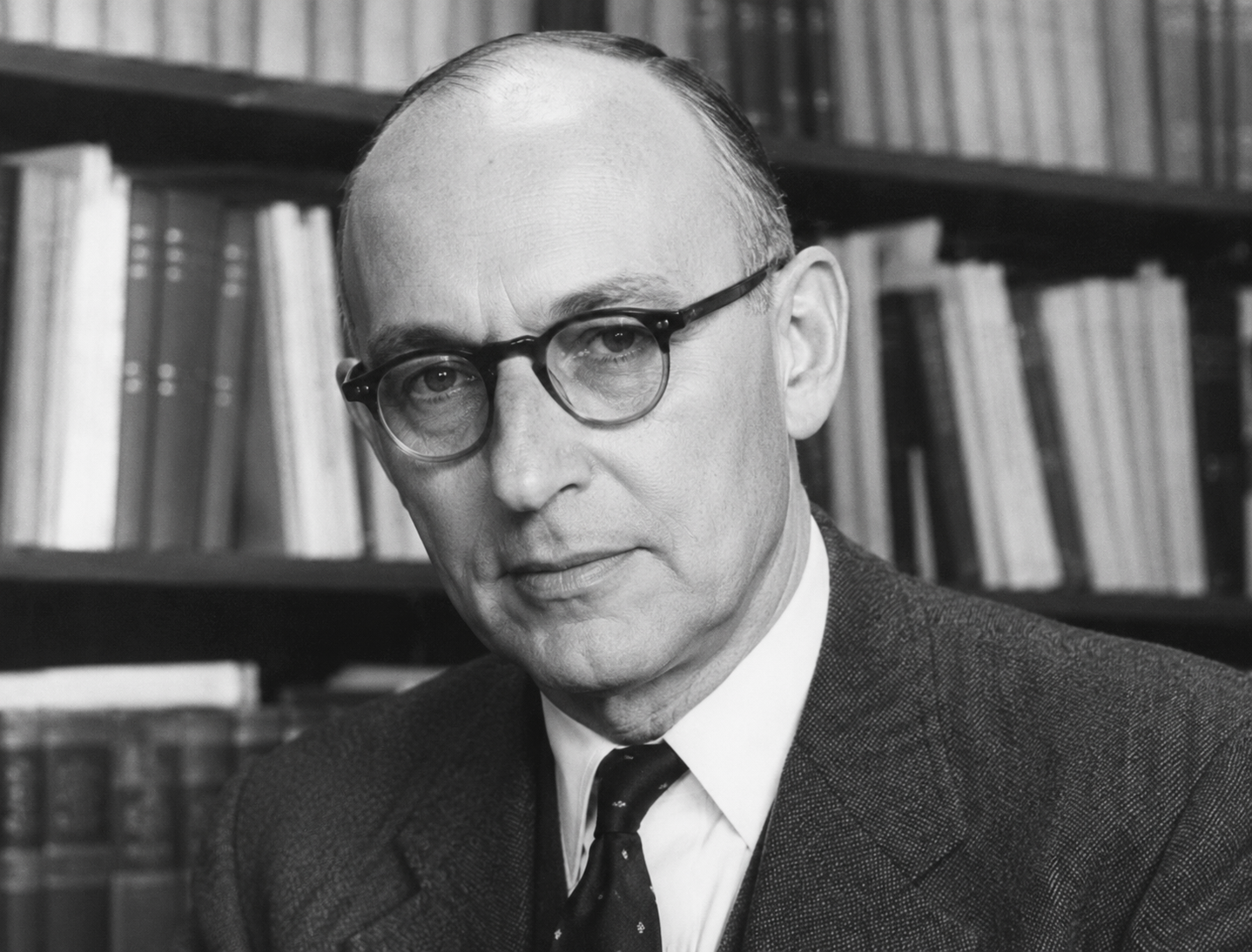 Retrato ilustrativo em preto e branco de Kurt Prober, com óculos, traje formal e livros ao fundo, em estilo fotográfico histórico.